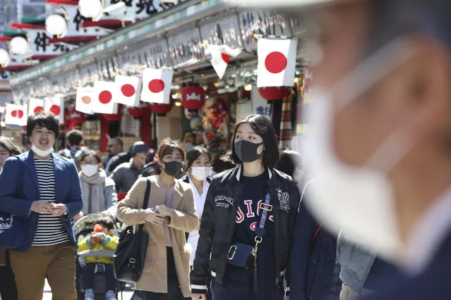 Visitors wearing face masks walk through Nakamise alley at Asakusa in Tokyo, Friday, March 20, 2020. (Photo by Koji Sasahara/AP Photo)