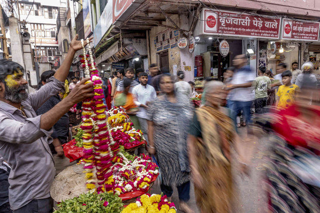 People walk by venders selling flowers Monday, April 15, 2024, in the holy city of in Vrindavan, India. Until recently, Indian widows were expected to follow the sociocultural codes of a patriarchal Hindu society that demands a woman lead a life of asceticism after a husband's death. The holy city of Vrindavan, which has thousands of temples, is known as the City of Widows because it has given shelter to thousands of these women. (Photo by David Goldman/AP Photo)