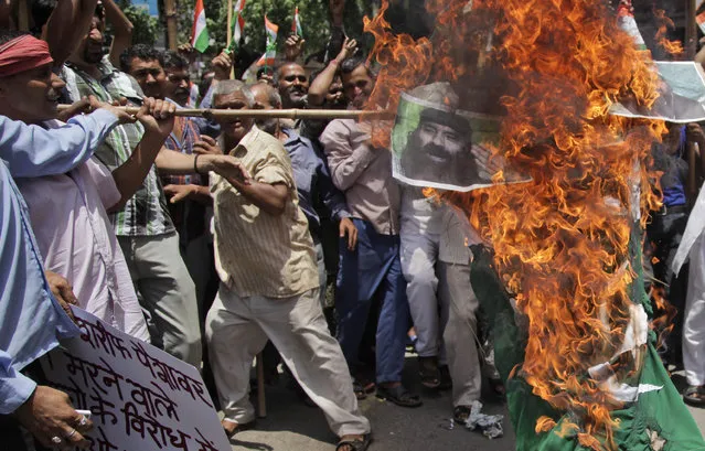 Activists of Hindu nationalist Shiv Sena party burn an effigy representing Pakistani Prime Minister Nawaz Sharif, Hizbul Mujahideen Syed Salahuddin, portrait seen, and Jama'at-ud-Da'wah chief Hafiz Muhammad Saeed during a protest against Pakistan, in Jammu, India, Tuesday, July 19, 2016. The protest was held against the Pakistan government for their decision to observe a countrywide 'black day' on July 19 to express solidarity with the people of Kashmir. (Photo by Channi Anand/AP Photo)