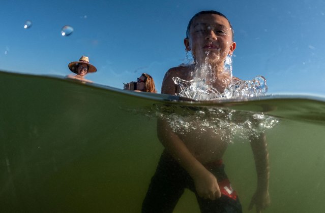 A kid refreshes himself at the Folsom lake, as California's grid operator urged the state's 40 million people to ratchet down the use of electricity in homes and businesses as a wave of extreme heat settled over much of the state, near Sacramento, California, U.S., August 15, 2022. (Photo by Carlos Barria/Reuters)