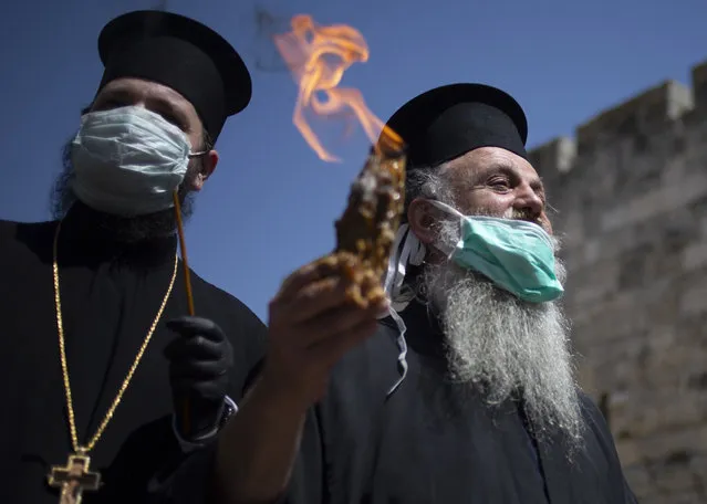 An Orthodox clergyman holds holy fire to transfer to predominantly Orthodox countries from the Church of the Holy Sepulchre, traditionally believed by many Christians to be the site of the crucifixion and burial of Jesus Christ, in Jerusalem's old city after the traditional Holy Fire ceremony was called off amid coronavirus, Saturday, April 18, 2020. A few clergymen on Saturday marked the Holy Fire ceremony as the coronavirus pandemic prevented thousands of Orthodox Christians from participating in one of their most ancient and mysterious rituals at the Jerusalem church marking the site of Jesus' tomb. (Photo by Ariel Schalit/AP Photo)