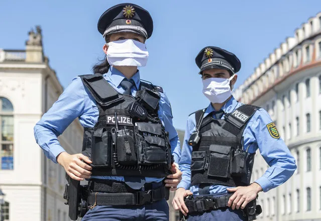 Police officers are standing at Neumarkt during a press appointment and wear mouthguards in Dresden, Germany, Tuesday, April 21, 2020. After a month of widespread standstill due to the containment of the corona virus in Germany, the first corona dressings will be gradually relaxed today, Monday, but masks will be mandatory in retail stores, buses and trains. (Photo by Robert Michael/dpa via AP Photo)