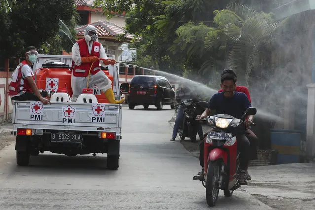 A members of Indonesian Red Cross stands on the back of a truck and sprays disinfectant in an attempt to curb the spread of new coronavirus outbreak at a neighborhood in Jakarta, Indonesia, Wednesday, April 8, 2020. (Photo by Achmad Ibrahim/AP Photo)