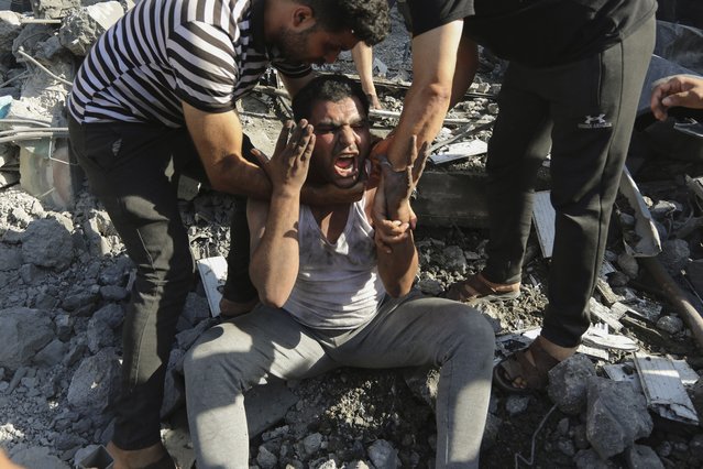 Palestinians comfort a crying man who lost relatives under the rubble of a house destroyed in an Israeli airstrike in Gaza City, Saturday, November 4, 2023. (Photo by Abed Khaled/AP Photo)