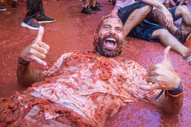 A reveler lays is tomato pulp during the Tomatina festival on August 31, 2022 in Bunol, Spain. The world's largest food fight festival, La Tomatina, consists of throwing overripe and low-quality tomatoes at each other. (Photo by Zowy Voeten/Getty Images)