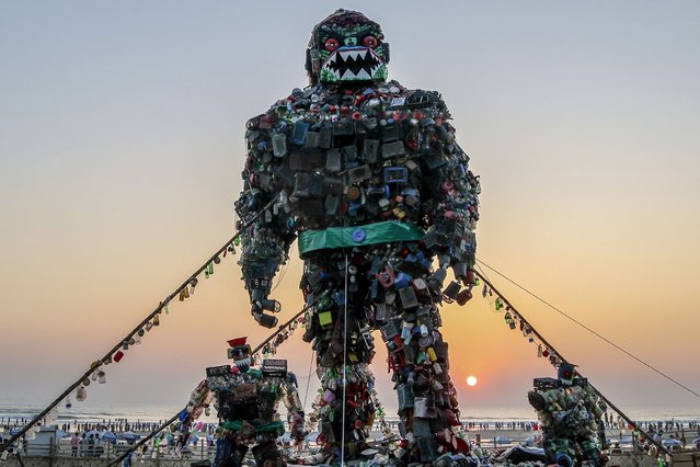 People walk past a giant sculpture of a “Robot Monster” made of plastic waste to raise awareness about the hazards of polluting the sea, at Cox's Bazar beach on December 5, 2024. (Photo by Abdul Goni/AFP Photo)