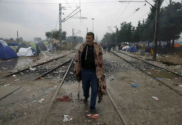 A Syrian refugee walks by a deserted camp at the border of Greece and Macedonia during a rainstorm, near the Greek village of Idomeni, September 10, 2015. (Photo by Yannis Behrakis/Reuters)