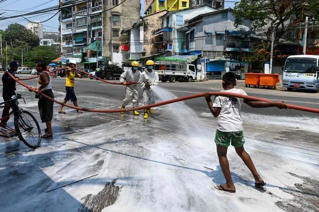 Firefighters and volunteers disinfect a street as a preventive measure to contain the spread of the COVID-19 coronavirus at Yangon on April 8, 2020. (Photo by Ye Aung Thu/AFP Photo)