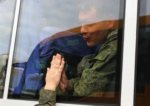 A reservist drafted during the partial mobilisation says goodbye to a loved one through a bus window before his departure for a military base, in Sevastopol, Crimea on September 27, 2022. (Photo by Alexey Pavlishak/Reuters)