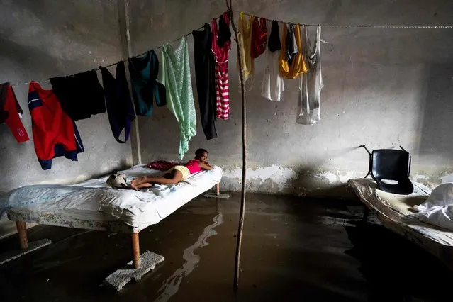 A girl lies on a bed at her flooded home in Batabano, Cuba, on September 27, 2022, during the passage of hurricane Ian. Hurricane Ian made landfall in western Cuba early Tuesday, with the storm prompting mass evacuations and fears it will bring widespread destruction as it heads for the US state of Florida. (Photo by Yamil Lage/AFP Photo)