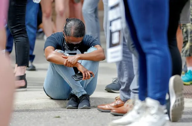 A woman sits on the curb as people stand to observe almost nine minutes of silence during a memorial service for George Floyd who died while in police custody in Minneapolis, Minnesota, U.S. June 4, 2020. (Photo by Eric Miller/Reuters)
