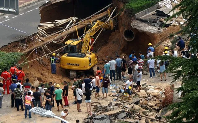 This photo taken on August 2, 2016 shows rescuers searching for missing people after a giant sinkhole opened up on a road in Zhengzhou, in central China's Henan province. Sinkholes are known geological phenomenona that usually occur predominantly in areas that have been heavily mined or on reclaimed land. (Photo by AFP Photo/Stringer)