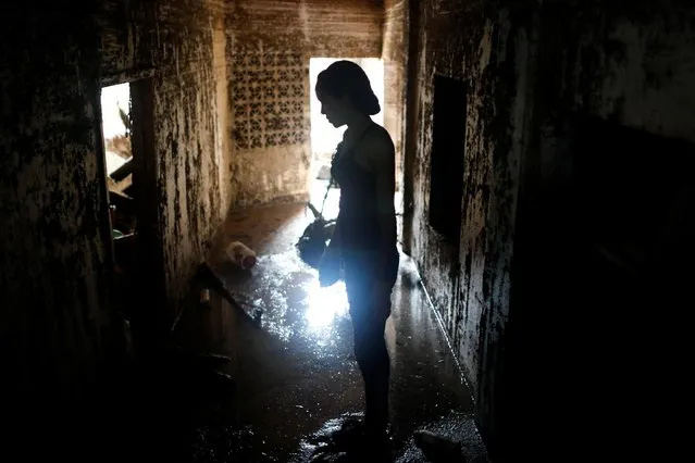 A woman stands inside a damaged building following a landslide due to heavy rains, in Las Tejerias, Aragua state on October 10, 2022. (Photo by Leonardo Fernandez Viloria/Reuters)