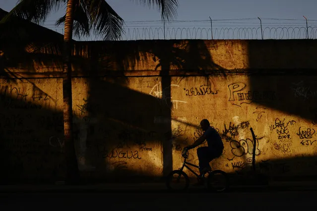 A man rides his bicycle near a graftti-covered wall in the north district neighborhood of Vasco da Gama outside of the Olympic periphery on Wednesday, August 17, 2016. (Photo by Aaron Ontiveroz/The Denver Post)