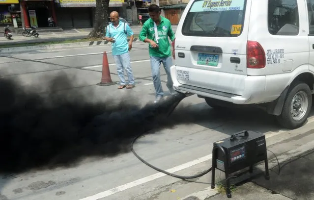 Personnel from the Philippine Department of Environment and Natural Resources (DENR) randomly check carbon emissions from commuter vehicles in suburban Manila on October 2, 2014. Clean air advocates composed of health professional, business, religious organizations and civil society are meeting and discussing October 2, concrete efforts to fight air pollution during the Clean Air Summit organized by the DENR. (Photo by Jay Directo/AFP Photo)