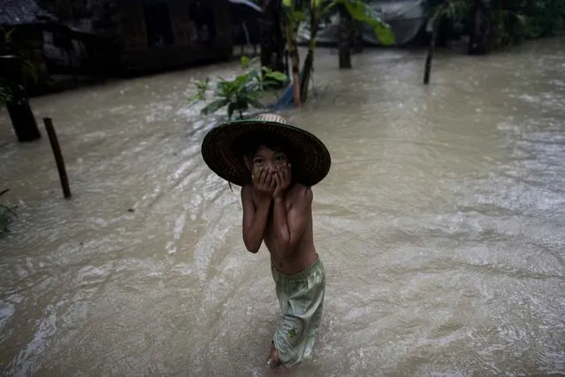 A child walks in floodwaters in Kyangyi Dauk village near Darka in Myanmar's Irrawaddy region on August 12, 2016. Myanmar’s Department of Relief and Resettlement reports 419,330 people have been affected by floodings in five regions and the two states of Mon and Kachin with five deaths from the period of July to August 9, 2016. (Photo by Ye Aung Thu/AFP Photo)