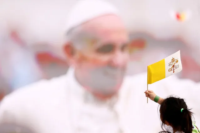 A child waves a Vatican City flag as people gather to attend a holy mass at Bahrain National Stadium during Pope Francis' apostolic journey, in Riffa, Bahrain, November 5, 2022. (Photo by Yara Nardi/Reuters)