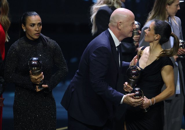 Brazil International Marta (L) looks on as FIFA President Gianni Infantino (C) goes to kiss Spain and Barcelona midfielder Aitana Bonmati (R) as the prize winners pose on stage during the Best FIFA Football Awards 2023 ceremony in London on January 15, 2024. (Photo by Adrian Dennis/AFP Photo)