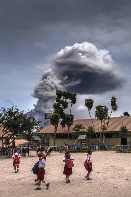 Students play as mount Sinabung volcano spews thick volcanic ash in Karo, North Sumatra province on August 30, 2016. Many residents in the area were forced to relocate to other villages in northern Sumatra located at a safer distance from mount Sinabung volcano, one of most active in Indonesia. (Photo by Tibta Pangin/AFP Photo)