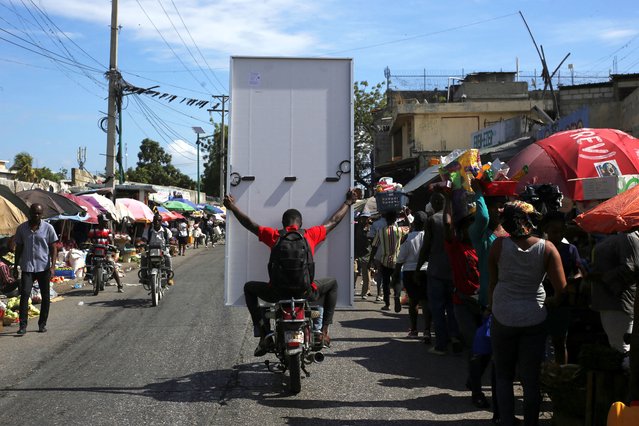 A man holds a solar panel as he flees his neighborhood near a protest against gang-related violence and to demand the resignation of Haiti's transitional presidential council in Port-au-Prince, Haiti, on March 26, 2025. (Photo by Jean Feguens Regala/Reuters)