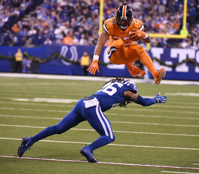 Denver Broncos running back Devontae Booker (23) leaps over Indianapolis Colts free safety Clayton Geathers (26) to avoid the tackle during the second quarter on December 14, 2017 in Indianapolis, Indiana at Lucas Oil Stadium. Booker ran it in for the touchdown but was called back due to a penalty on the play. (Photo by John Leyba/The Denver Post)