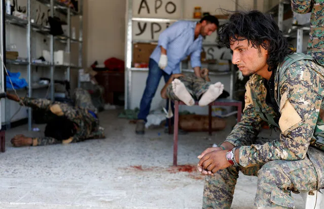 A Syrian Democratic Forces (SDF) fighter sit as medics treat his comrades injured by sniper fired by Islamic State militants in a field hospital in Raqqa, Syria, June 28, 2017. (Photo by Goran Tomasevic/Reuters)