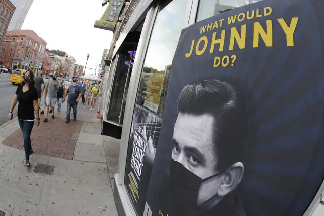 A poster showing country music legend Johnny Cash wearing a mask is attached to a storefront Wednesday, August 5, 2020, in Nashville, Tenn. The wearing of face coverings is required in most public indoor and outdoor situations in Nashville due to an increase of COVID-19 cases. (Photo by Mark Humphrey/AP Photo)