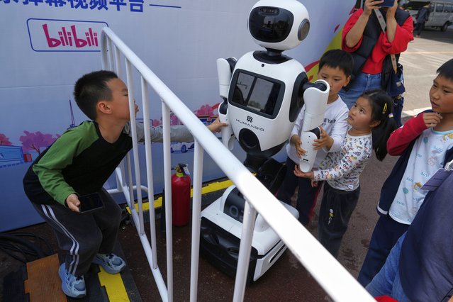 Children react to a wheeled robot after the Humanoid Robot Half-Marathon held in Beijing on Saturday, April 19, 2025. (Photo by Ng Han Guan/AP Photo)