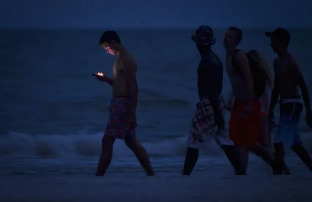 A person looks at his cell phone as he and others walk along the beach at twilight during the Labour Day long weekend in Ft Myers Beach, Florida August 31, 2014. U.S. regulators, on July 14, 2016, paved the way for a lightning fast next generation of wireless services in a move that made the United States the first country to set aside an ample amount of airwaves for so-called 5G wireless applications and networks. (Photo by Carlo Allegri/Reuters)
