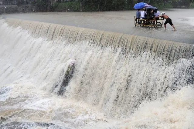 Residents cross a swelling dam, due to rising waters brought about by Typhoon Koppu, in Las Pinas city, metro Manila October 19, 2015. Typhoon Koppu swept across the northern Philippines killing at least nine people as trees, power lines and walls were toppled and flood waters spread far from riverbeds, but tens of thousands of people were evacuated in time. (Photo by Ezra Acayan/Reuters)