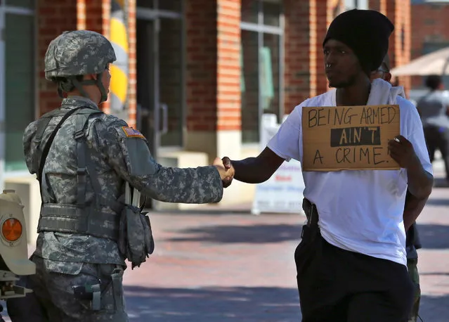 An armed protester greets a national guard soldier as he takes part in a march through the streets to protest the police shooting of Keith Scott in Charlotte, North Carolina, U.S., September 24, 2016. (Photo by Mike Blake/Reuters)
