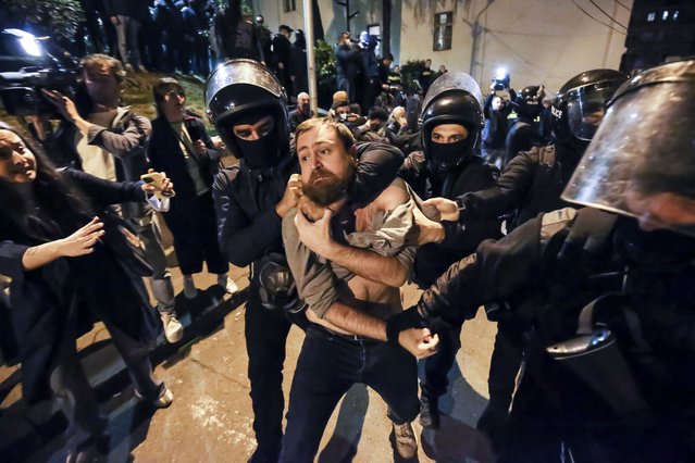 Police officers detain a protestor as other gather outside the parliament building in Tbilisi, Georgia, on Tuesday, April 16, 2024, to protest against “the Russian law” similar to a law that Russia uses to stigmatize independent news media and organizations seen as being at odds with the Kremlin. (Photo by Zurab Tsertsvadze/AP Photo)
