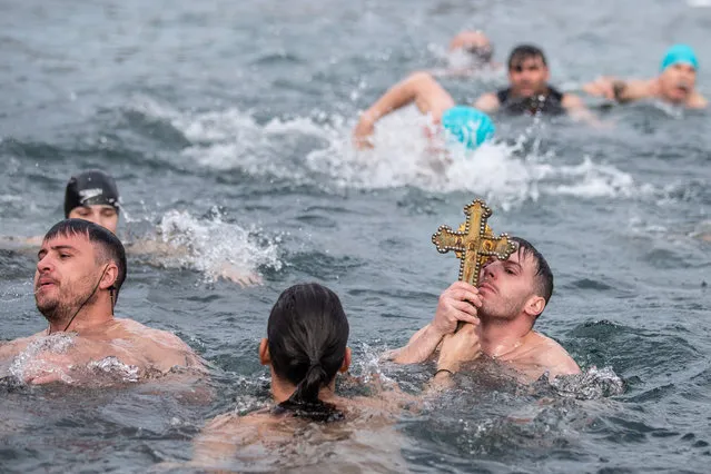 Greek Orthodox faithful kisses a wooden cross after retrieving it from the waters of the Golden Horn during the blessing of the water ceremony, as part of Epiphany day celebrations at the Church of Fener Orthodox Patriarchate on January 06, 2023 in Istanbul, Turkey. Epiphany celebrates the baptism of Jesus Christ by John the Baptist, and falls on the 12th and final day of Christmas. (Photo by Burak Kara/Getty Images)