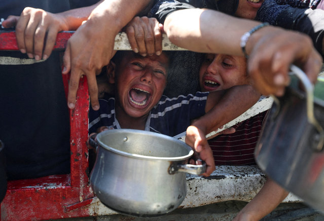 Palestinians wait to receive food from a charity kitchen, amid a hunger crisis, in Gaza City on July 23, 2025. (Photo by Mahmoud Issa/Reuters)
