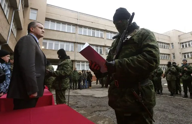 Sergei Aksyonov, Crimea's pro-Russian prime minister, stands as a member of a pro-Russian self defence unit swears an oath to the Crimean government in Simferopol, in this March 10, 2014 file photo. (Photo by Vasily Fedosenko/Reuters)