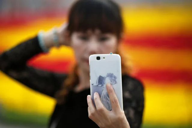 A woman takes pictures of herself as people gather in Tiananmen Square to celebrate National Day marking the 67th anniversary of the founding of the People's Republic of China, in Beijing October 1, 2016. (Photo by Damir Sagolj/Reuters)