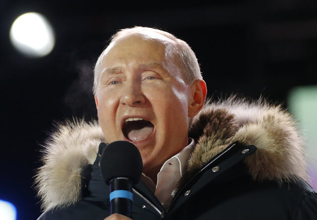 Russian President Vladimir Putin speaks to supporters during a rally near the Kremlin in Moscow, Sunday, March 18, 2018. An exit poll suggests that Vladimir Putin has handily won a fourth term as Russia's president, adding six more years in the Kremlin for the man who has led the world's largest country for all of the 21st century. (Photo by Alexander Zemlianichenko/AP Photo)