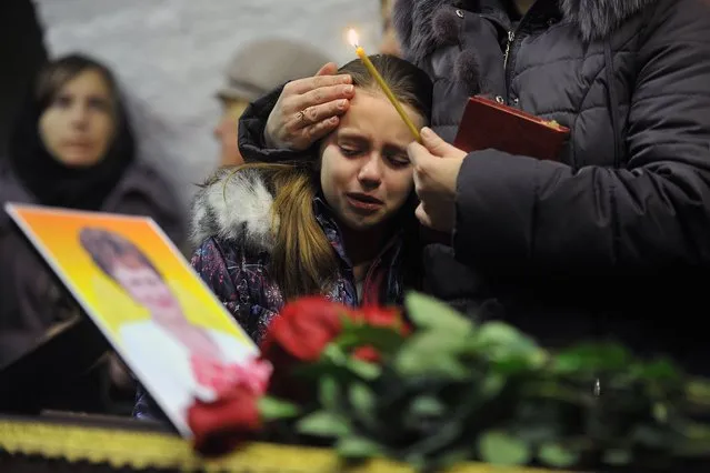 A girl cries during a funeral service for Nina Lushchenko, 60, a victim of the Russian MetroJet Airbus A321 crash, at a church in Velikiy Novgorod on November 5, 2015 ahead of her burial. Russian airline Kogalymavia's flight 9268 crashed en route from Sharm el-Sheikh to Saint Petersburg on October 31, killing all 224 people on board, the vast majority of them Russian tourists. (Photo by Olga Maltseva/AFP Photo)