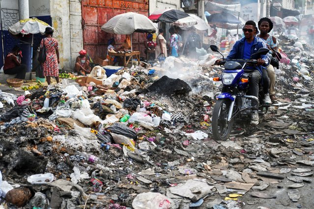 A motorcycle driver navigates a street covered with trash in downtown in Port-au-Prince, Haiti, Wednesday, October 15, 2025. (Photo by Odelyn Joseph/AP Photo)