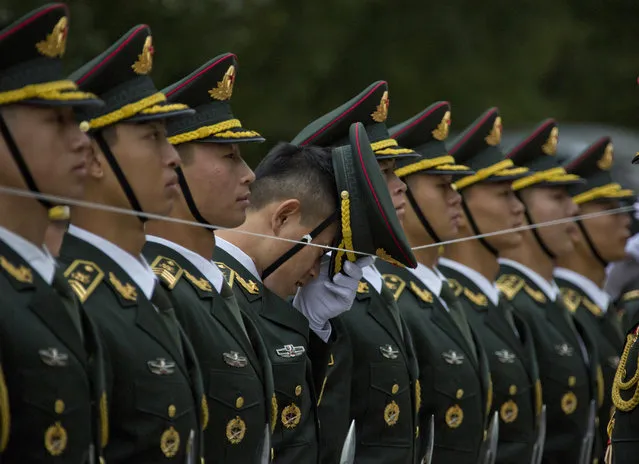 A member of a Chinese honor guard adjusts his cap as they line up with the help of a string before a welcome ceremony for Philippine President Rodrigo Duterte outside the Great Hall of the People in Beijing, China, Thursday, October 20, 2016. (Photo by Ng Han Guan/AP Photo)