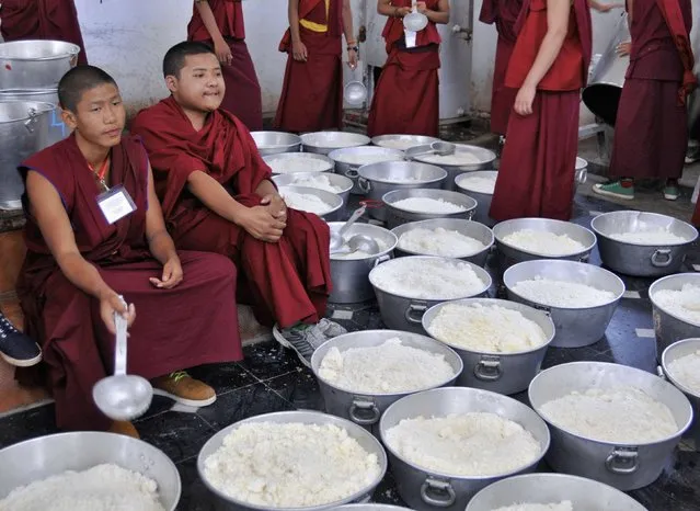 Young Buddhist monks wait to serve cooked rice to the attendees of the Jangchup Lamrim teachings conducted by the exiled Tibetan spiritual leader the Dalai Lama (unseen) at the Gaden Jangtse Thoesam Norling Monastery in Mundgod in the southern Indian state of Karnataka December 28, 2014. (Photo by Abhishek N. Chinnappa/Reuters)
