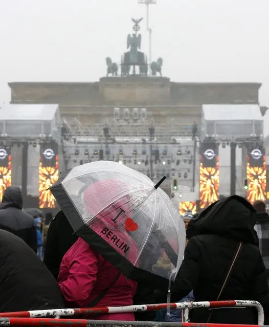 A woman uses an umbrella to protect herself from rain during New Year celebrations at the Brandenburger Tor gate in Berlin December 31, 2014. (Photo by Fabrizio Bensch/Reuters)
