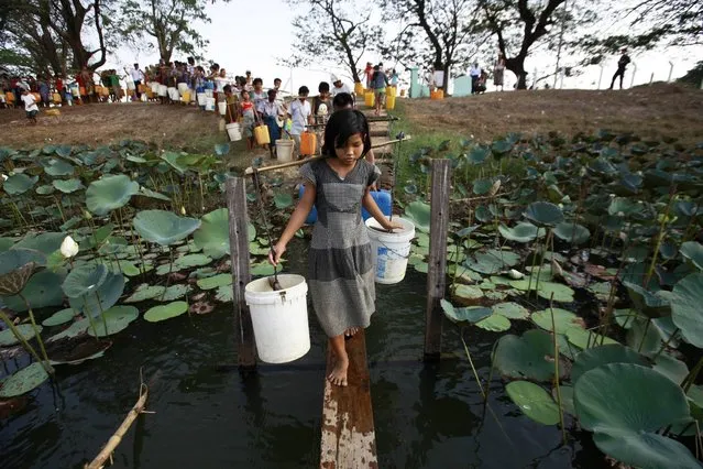 People line up to collect water at Yazarthingyan lake in Dala township, near Yangon May 12, 2013. Dala township is located near the sea and the only source of freshwater is from the inland lakes which have all dried up, with the exception of Yazarthingyan lake. According to the local authorities, the lake is only opened to locals once every three days, with over 1,000 people lining up to collect water when the authorities opened the lake from 4 pm to 5 pm. (Photo by Soe Zeya Tun/Reuters)