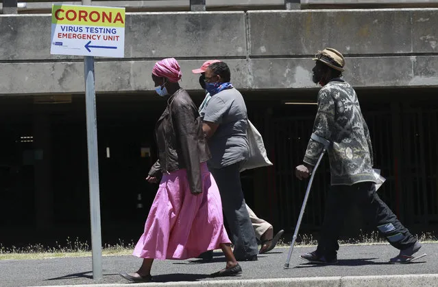 People pass a sign at Groote Schuur Hospital in Cape Town, South Africa, indicating a COVID testing station Tuesday, December 29, 2020. South African President Cyril Ramaphosa has declared the wearing of masks compulsory and has reimposed a ban on the sales of alcohol and ordered the closure of all bars and beaches as part of new restrictions to help the country battle a resurgence of the coronavirus, including a new variant. (Photo by Nardus Engelbrecht/AP Photo)