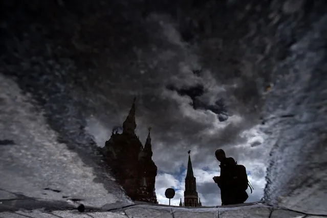 A man is reflected in a puddle as he walks across Moscow's Red Square on August 18, 2015. (Photo by Kirill Kudryavtsev/AFP Photo)
