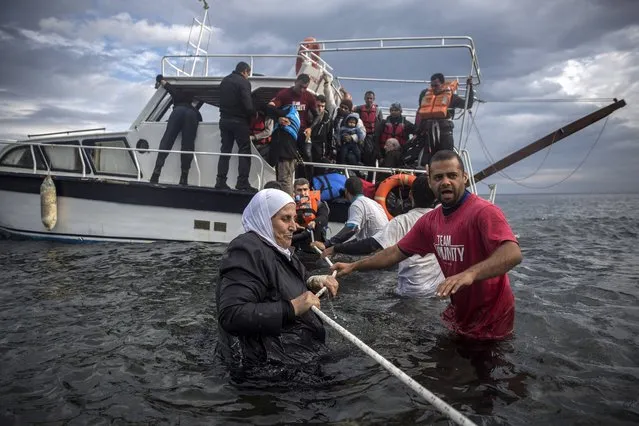 Volunteers help refugees and migrants to disembark from a vessel after their arrival from the Turkish coast to the northeastern Greek island of Lesbos, Wednesday, November 25, 2015. About 5,000 migrants reaching Europe each day over the so-called Balkan migrant route. The refugee crisis is stoking tensions among the countries on the so-called Balkan migrant corridor — Greece, Macedonia, Serbia, Croatia and Slovenia. (Photo by Santi Palacios/AP Photo)