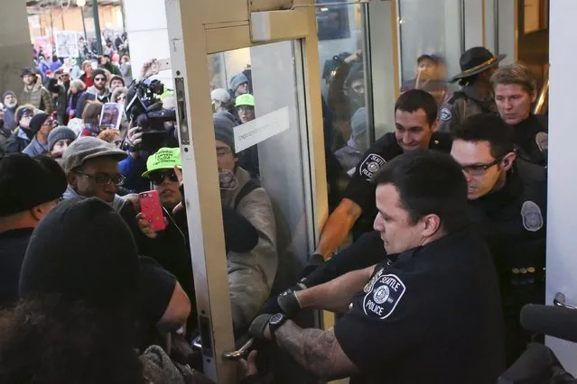 Police attempt to close a door and block Black Lives Matter protesters from entering Westlake Mall on Black Friday in Seattle, Washington November 27, 2015. (Photo by David Ryder/Reuters)