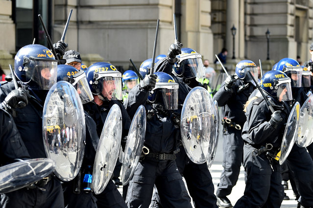 Police officers in riot gear gesture with batons during the 'Enough is Enough' demonstration held in reaction to the fatal stabbings in Southport on July 29, outside the Liver Building in Liverpool on August 3, 2024. UK police prepared for planned far-right protests and other demonstrations this weekend, after two nights of unrest in several English towns and cities following a mass stabbing that killed three young girls. (Photo by Peter Powell/AFP Photo)
