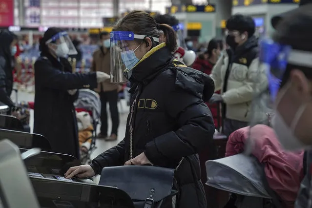 A woman wearing a face mask and face shield to help curb the spread of the coronavirus prepares to board her train at the South Train Station in Beijing, Thursday, January 28, 2021. (Photo by Andy Wong/AP Photo)