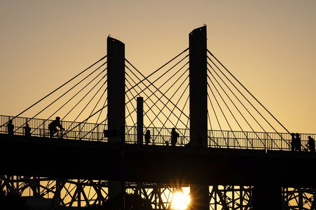 Poeple walk across the Big Four Bridge as the sun sets at Waterfront Park on Sunday, June 22, 2025, in Louisville, Ky. (Photo by Jon Cherry/AP Photo)